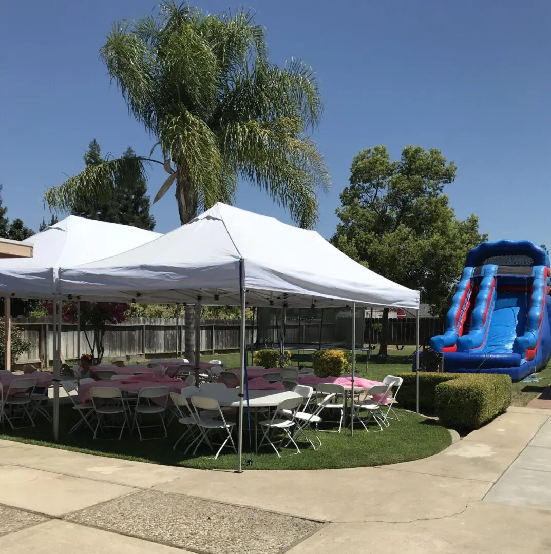 A large white tent with tables and chairs in the middle.