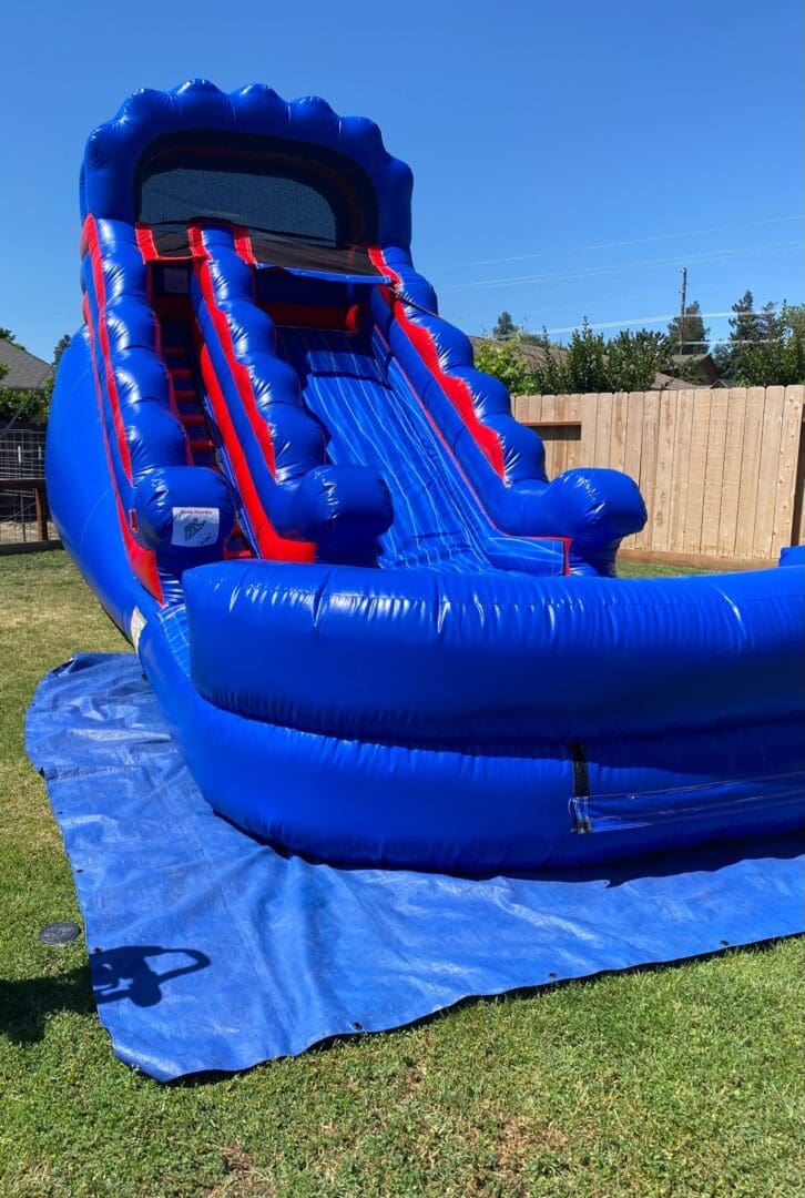 A blue and red inflatable slide on top of a lawn.