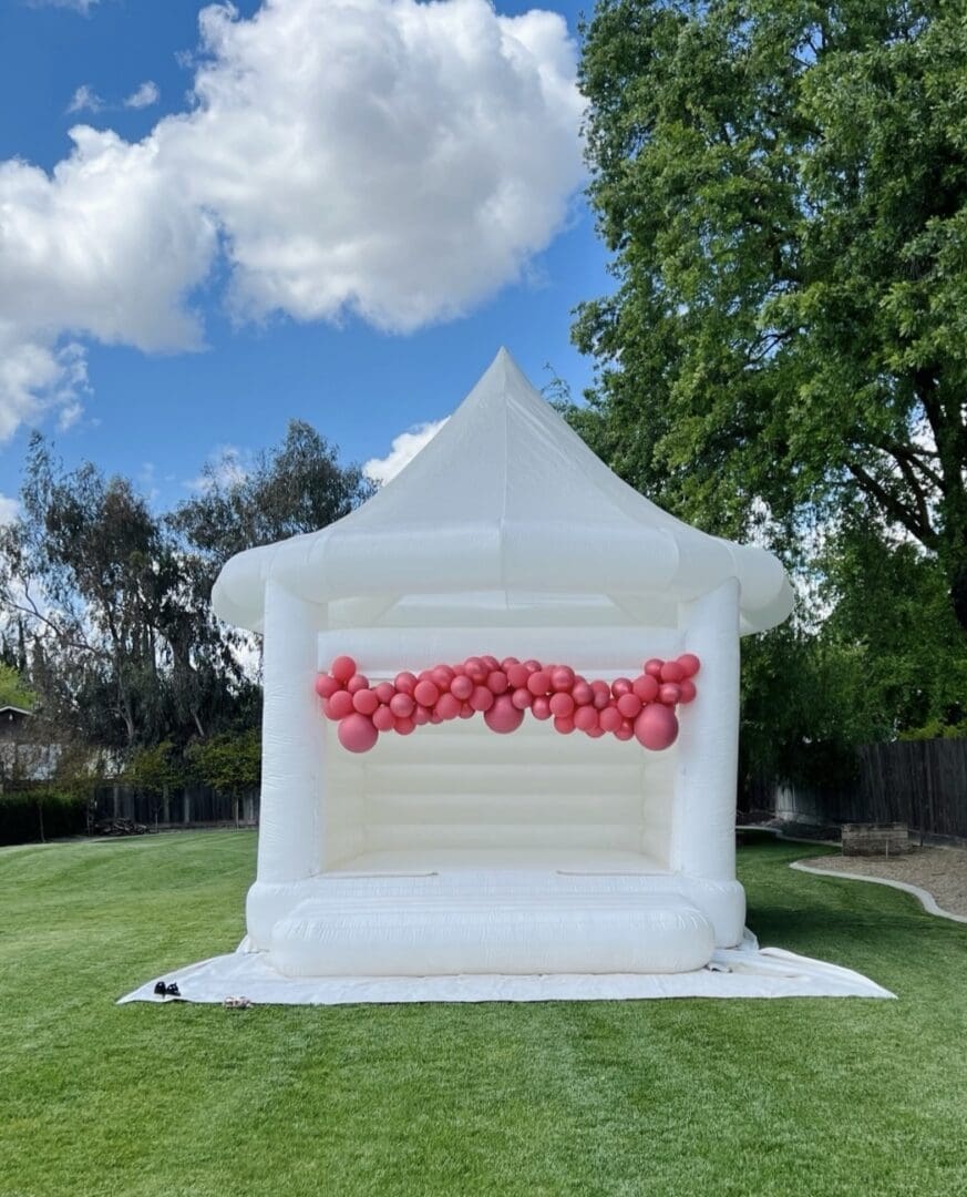 A white inflatable tent with balloons on it.